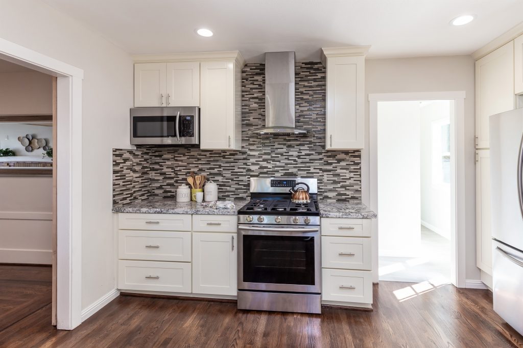 Kitchen with white cabinets and mixed grey tiled backsplash